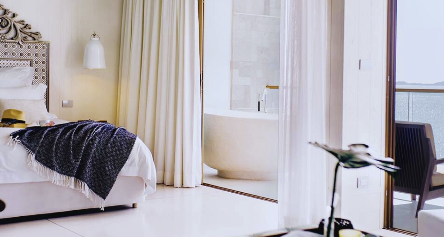 Hotel king bed with a freestanding bathtub and ocean-view balcony
